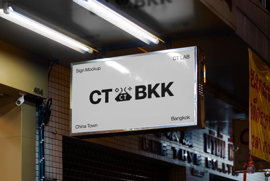 Clean white storefront sign showing CT BKK logo under bright linear lights on dark street